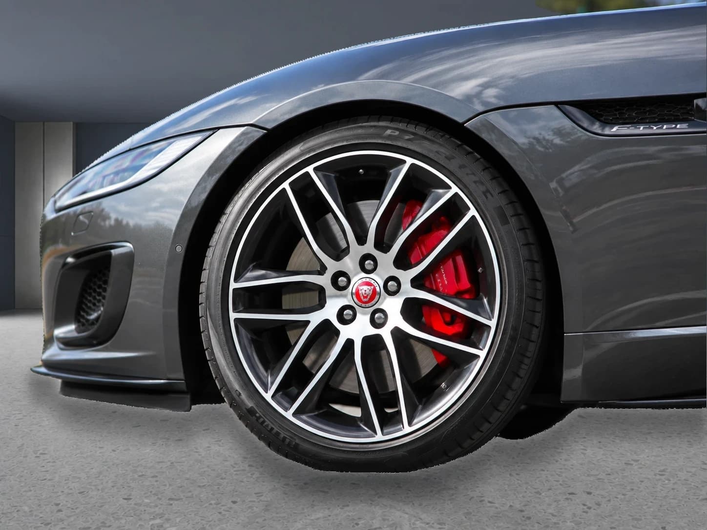 Prepared close-up of the Jaguar F-Type front wheel and red brake caliper in a neutral showroom