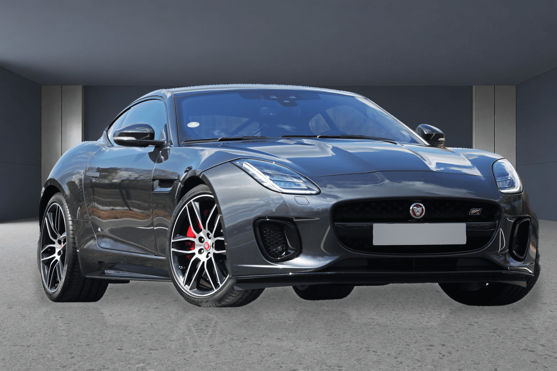 Prepared gray Jaguar F-Type in a neutral showroom with its license plate masked